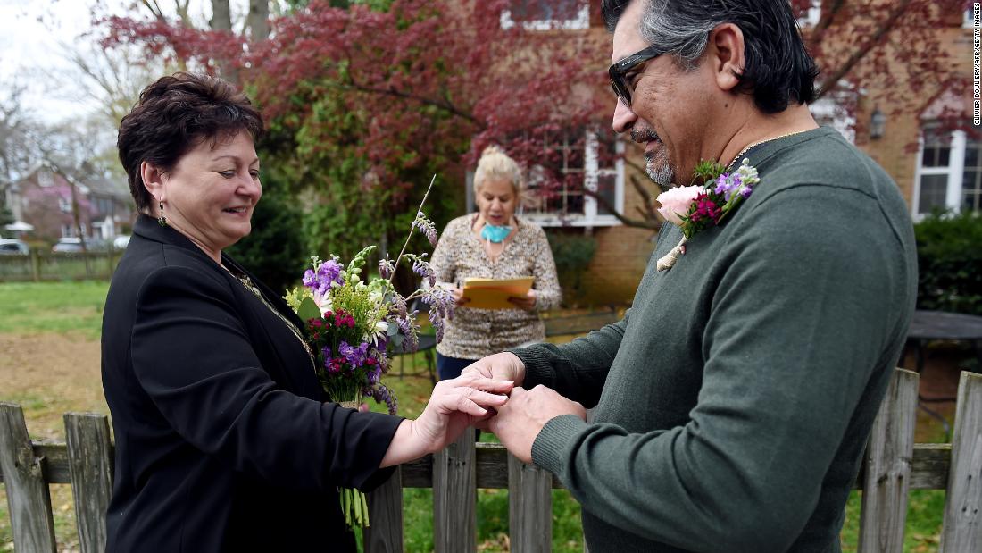 A newly married couple exchange wedding rings in front of the home of a Virginia state marriage officiant in Arlington, Virginia, on April 1.