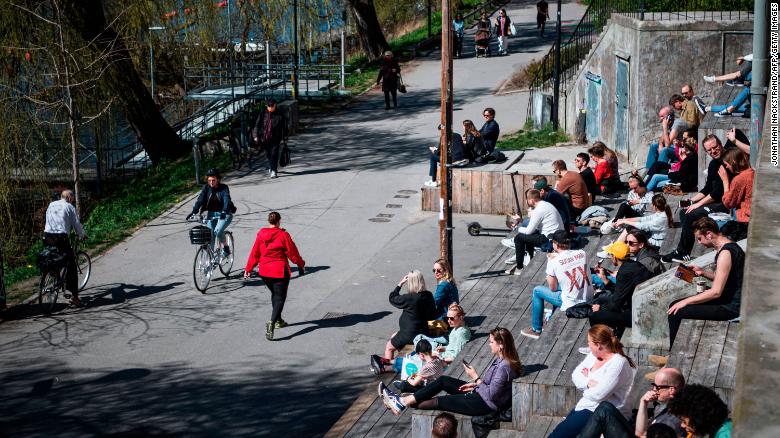 People enjoy the warm spring weather as they sit by the water at Hornstull in Stockholm on April 21 during the COVID-19 pandemic. 
