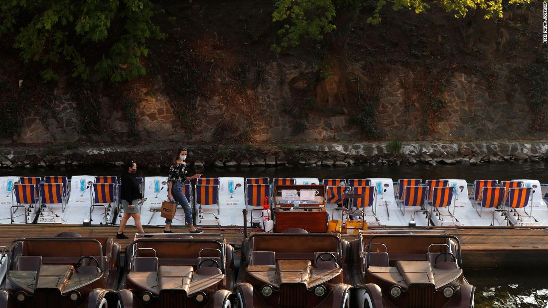 Two women walk to rent a small paddle boat by the Vltava River in Prague, Czech Republic, on April 17, 2020.