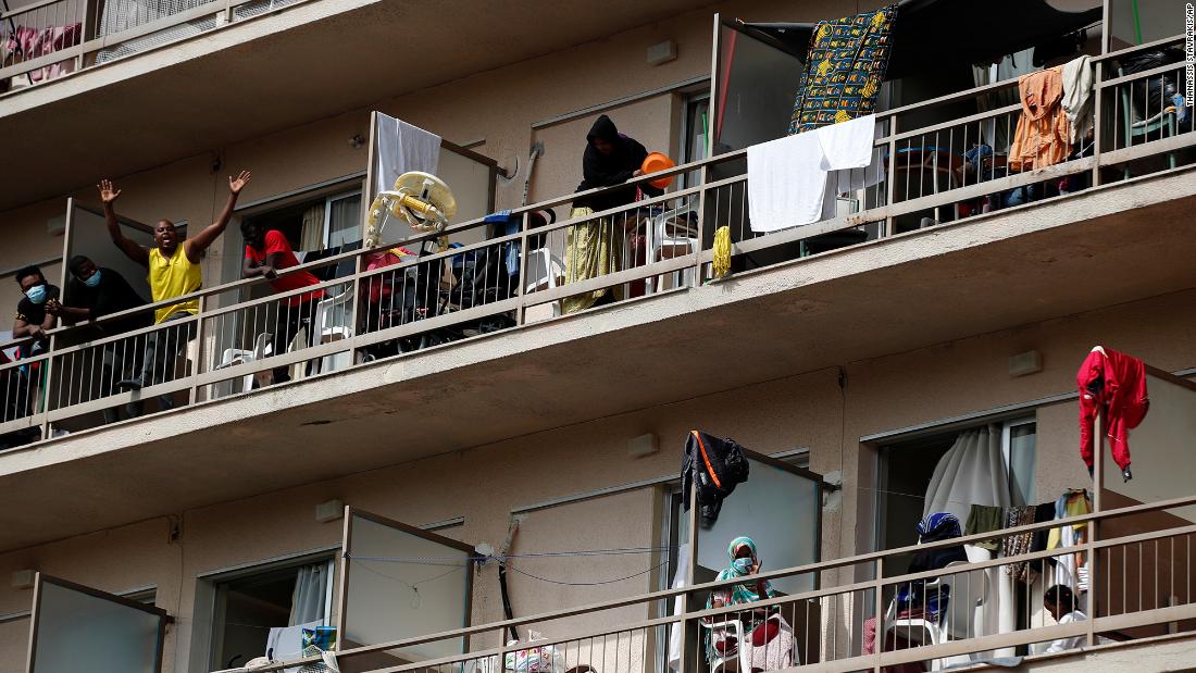 Migrants wave from balconies at a hotel in Kranidi, Greece, on April 21, 2020. The shelter, which hosts 470 asylum seekers, was placed in isolation after a pregnant resident tested positive for the novel coronavirus.