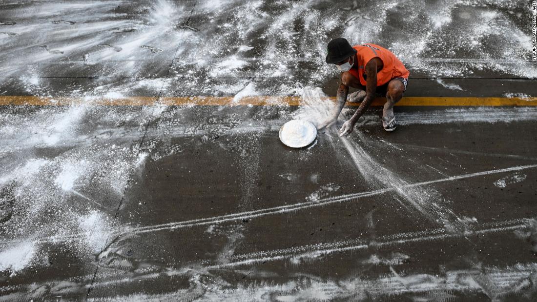 A volunteer in Yangon, Myanmar, spreads calcium oxide on a road to help prevent the spread of the coronavirus on April 22, 2020.