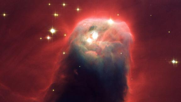 The Cone Nebula is a turbulent star-forming pillar of gas and dust. It's 7 light-years long, but this image taken by Hubble in 2002 shows the top 2.5 light-years (which equals 23 million round trips to the moon). Ultraviolet radiation causes the hydrogen gas to emit an eerie red glow.