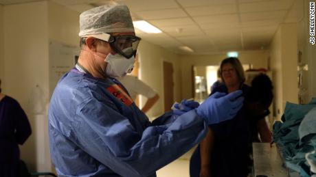 Dr. Roger Townsend dons PPE before entering the critical care unit.