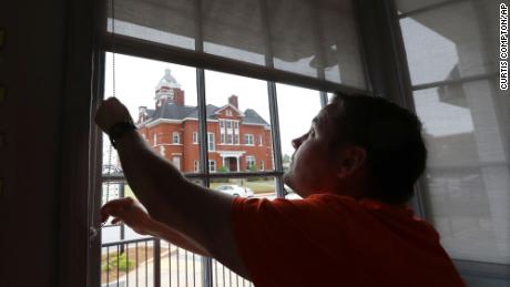 Brian Lambert, owner of a coffee and sweets shop in Forsyth, Ga., opens up the windows of his business as he gets ready to reopen next week. 