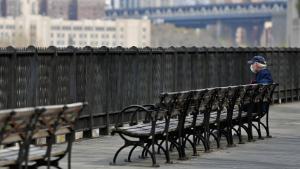 A man sits alone on a bench overlooking part of the Manhattan skyline amid the Coronavirus pandemic on April 21, 2020 in the Brooklyn Borough of New York City. (Photo by Angela Weiss / AFP) (Photo by ANGELA WEISS/AFP via Getty Images)
