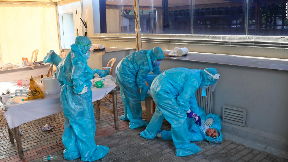 Health workers at a coronavirus testing center in New Delhi attend to a colleague who fainted due to exhaustion on April 27, 2020. 