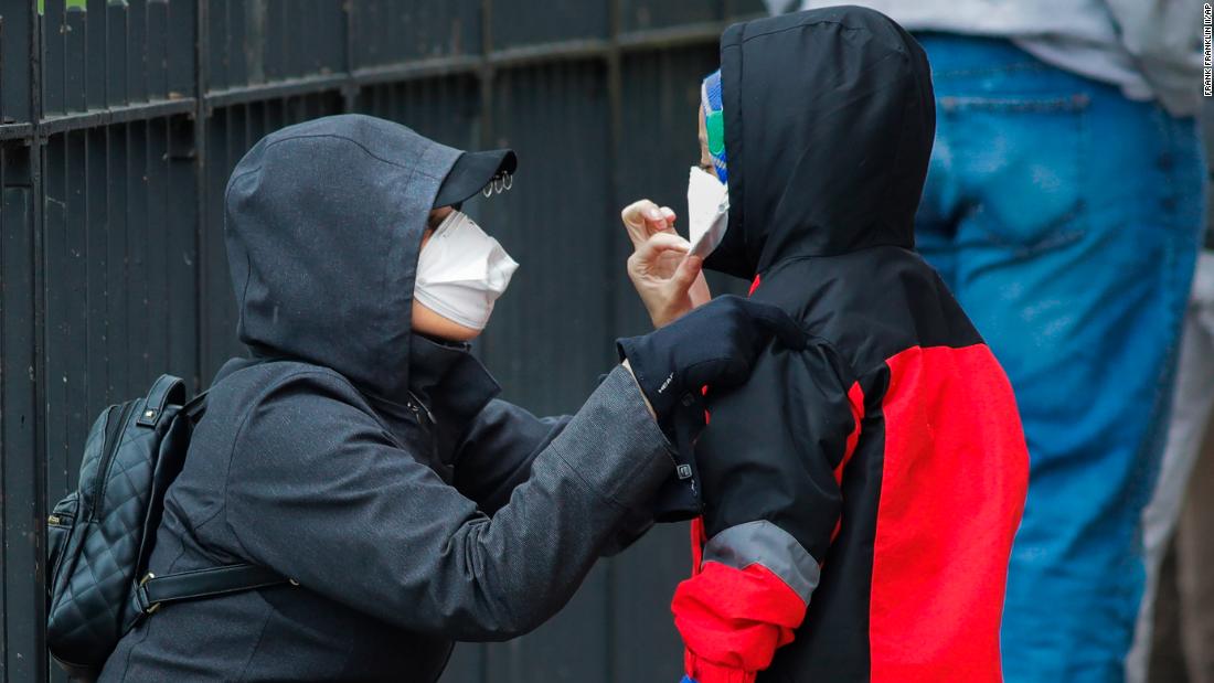 A woman adjusts her child's mask as they wait in line to be screened for Covid-19 in New York. 