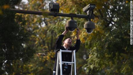 A worker adjusts security cameras on the edge of Tiananmen Square in Beijing on September 30, 2014.