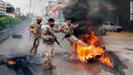 Lebanese soldiers remove burning tires placed by anti-government protesters to block a road.