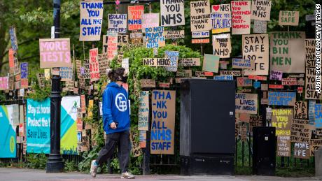 A woman in a face mask walks past signs in support of the NHS and key workers in East London on April 25.