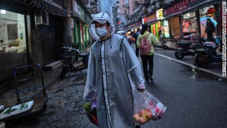 A person wearing a face mask as a preventive measure against the spread of the COVID-19 novel coronavirus carries groceries in a neighbourhood in Wuhan in China's central Hubei province on April 20, 2020. - A bride in a white gown poses by Wuhan's East Lake while a grandfather swings his tiny grandson in a hammock strung between trees, and families enjoy a picnic on a sunny afternoon: Wuhan is returning to normal after enduring a 76-day quarantine. (Photo by Hector RETAMAL / AFP) / TO GO WITH Health-virus-China-Wuhan,FOCUS by Jing Xuan Teng (Photo by HECTOR RETAMAL/AFP via Getty Images)