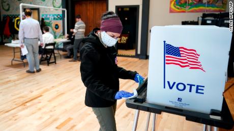 Shanon Hankin, cleans a voter booth after it was used for voting at the Wil-Mar Neighborhood Center Tuesday,  April 7, 2020 in Madison, Wis.  Voters across the state are ignoring a stay-at-home order in the midst of a pandemic to participate in the state&#39;s presidential primary election. (Steve Apps/Wisconsin State Journal via AP)