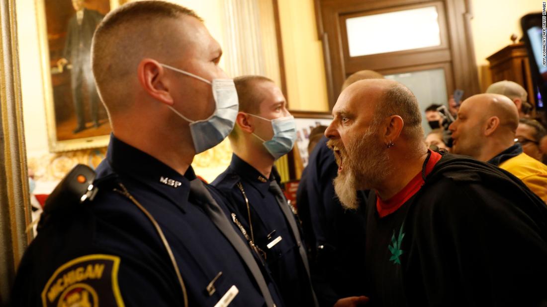 Michigan state police prevent protesters from entering the chamber of the Michigan House of Representatives on April 30, 2020. The protesters were unhappy with the state&#39;s stay-at-home order. Gov. Gretchen Whitmer recently extended the order through May 15, though restrictions were relaxed so some businesses could reopen.