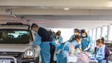 Les praticiens médicaux effectuant des tests pour Covid-19 dans une installation de test au volant d'un parking le 30 avril à Melbourne, en Australie. 