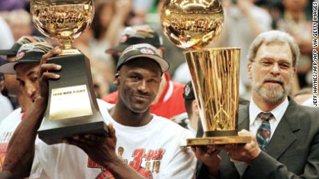 Jordan, seen here with Phil Jackson, raises his NBA Finals MVP trophy.