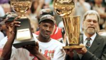 Jordan, seen here with Phil Jackson, raises his NBA Finals MVP trophy.