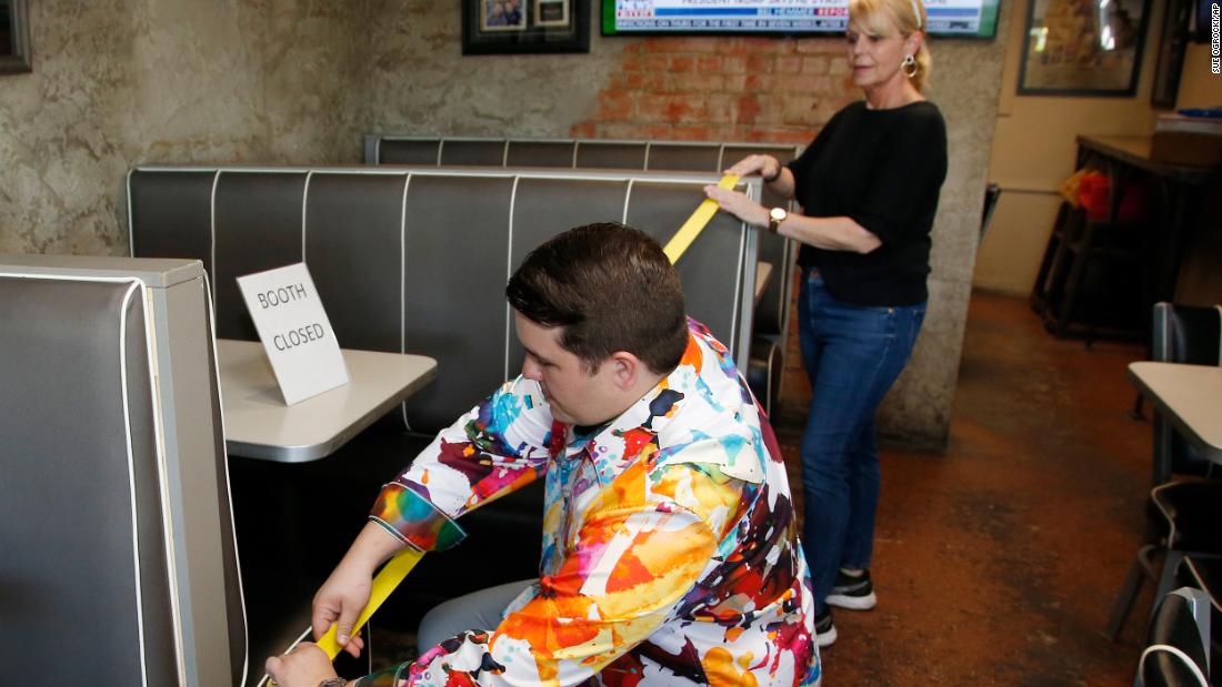 Leslie Wilson helps her son, JP, tape off booths at Falcone&#39;s Pizzeria in Oklahoma City on April 30. Restaurants in Oklahoma City were being allowed to reopen, and Falcone&#39;s Pizzeria closed some booths to allow for social distancing.