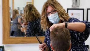 Denise Gravitt, top, cuts the hair of client Lisa Murray, bottom, at her salon, Beehive Salon, Friday, May 1, 2020, in Edmond, Okla., the first day hair salons have been allowed to reopen in Edmond following shutdowns due to coronavirus concerns. 