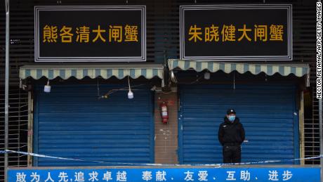 TOPSHOT - A security guard stands outside the Huanan Seafood Wholesale Market where the coronavirus was detected in Wuhan on January 24, 2020 - The death toll in China&#39;s viral outbreak has risen to 25, with the number of confirmed cases also leaping to 830, the national health commission said. (Photo by Hector RETAMAL / AFP) (Photo by HECTOR RETAMAL/AFP via Getty Images)