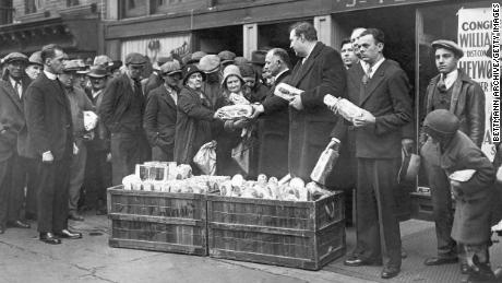 Reverend Raymond Brown and others hand out packages of food to the jobless outside St. Peter&#39;s Mission in New York City during the Depression.