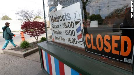 A woman walks past a closed barber shop, Wednesday, May 6, 2020, in Cleveland. (AP Photo/Tony Dejak)