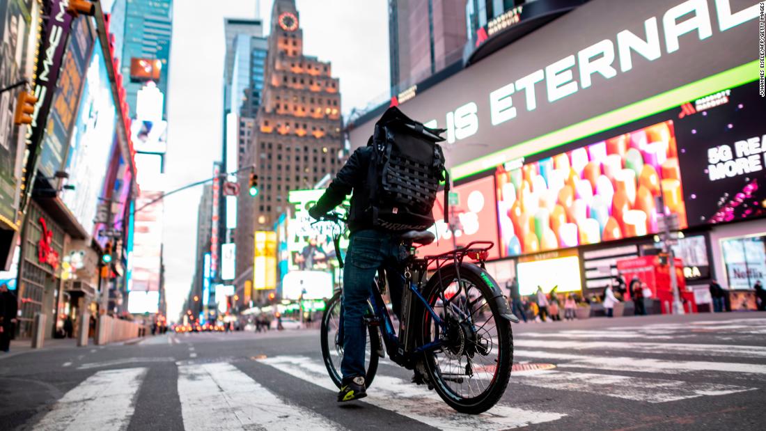 A food delivery worker crosses the street in New York&#39;s Times Square on March 17. Food delivery workers have become essential in the city after restaurants and bars closed. 
