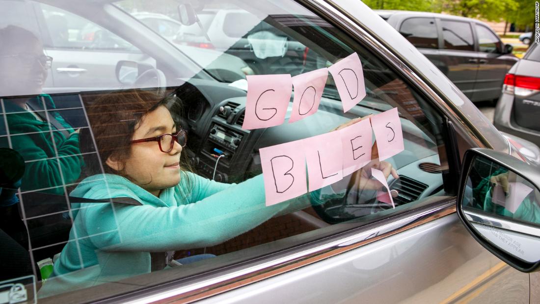 Elizabeth Ruiz, 7, puts up Post-It notes that spell out &quot;God Bless U&quot; as she and her mother, Daylin Lemus, wait in a line of hundreds of cars at a food bank in Hyattsville, Maryland, on May 5. &quot;This is the first food bank we have come to,&quot; Lemus said. &quot;My income is less than before, so we are coming in case things get worse. I&#39;m worried about stores running out of chicken. I have been looking for two weeks and can&#39;t find it anywhere.&quot; 