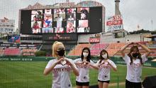 Cheerleaders pose in front of a big screen displaying baseball fans cheering from their homes during the opening game of South Korea&#39;s new baseball season between the SK Wyverns and Hanwha Eagles at Munhak Baseball Stadium in Incheon on Tuesday.
