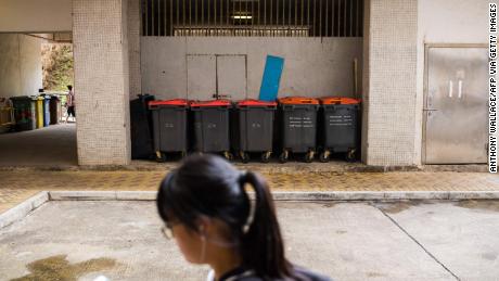 A girl walks past large trash bins at housing estate where the 2018 rat hepatitis patient lived. A rat infestation was found in the estate.