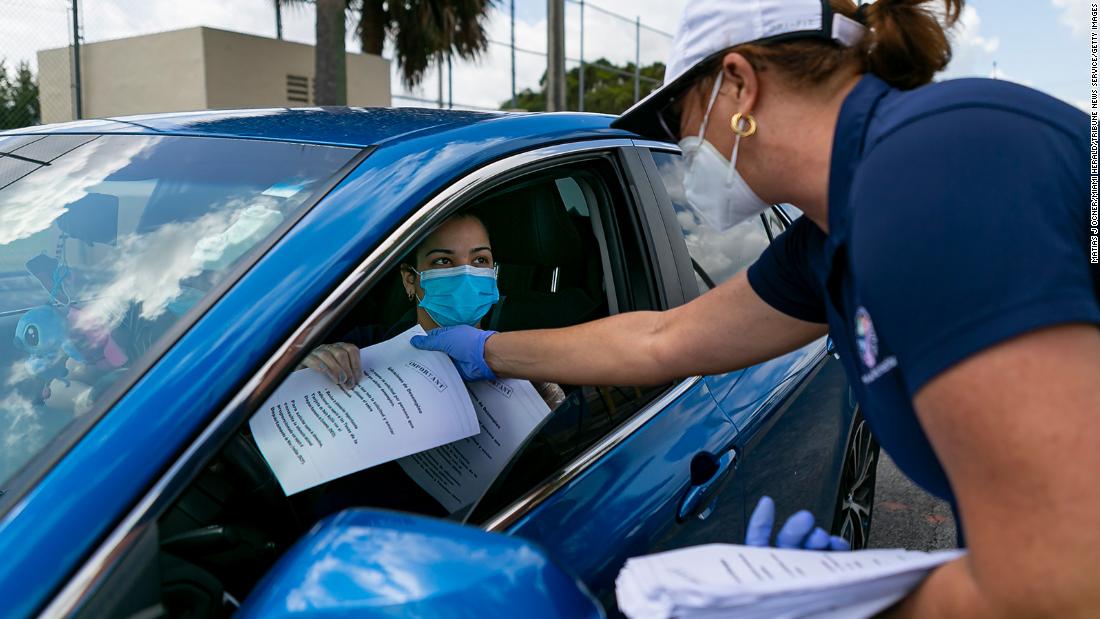 City employee Tatiana Fernandez distributes unemployment forms outside the John F. Kennedy Library in Hialeah, Florida, on April 7.