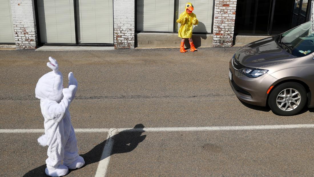 Landon Phillips, dressed as the Easter Bunny, and Boston Phillips, dressed as a chick, wave to cars in Newton, Massachusetts, during a drive-thru photo session at StoryHeights Church on April 11.