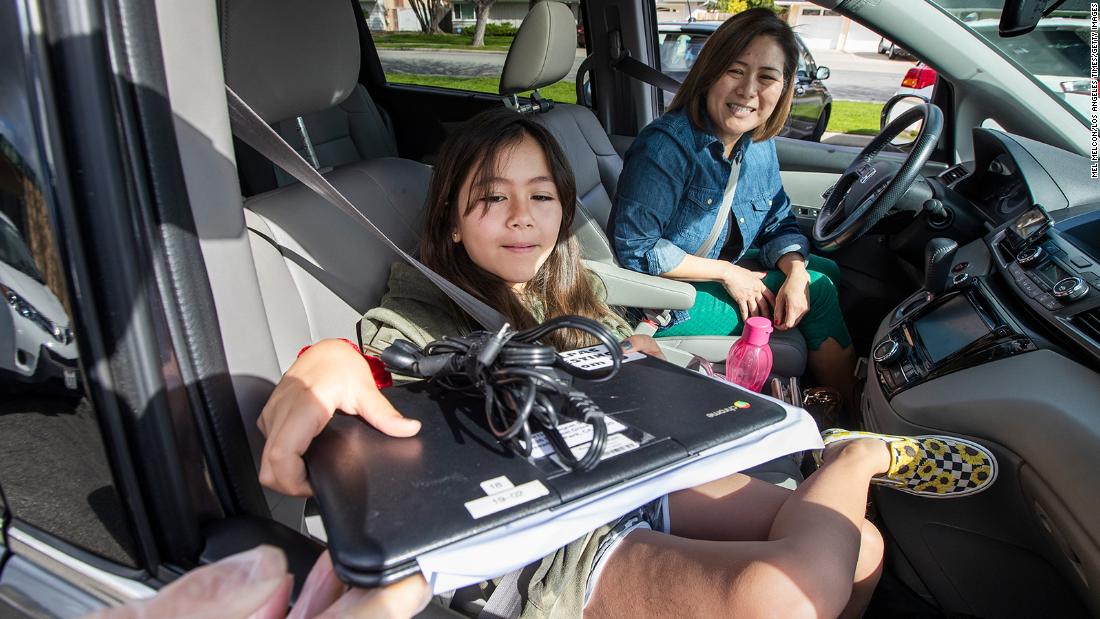 Denise Young looks on as her daughter Allison receives a portable computer in Newbury Park, California, on March 25. Around 75 Chromebooks, to be used for online instructions, were issued to students for free at a drive-thru and walk-up area in front of the school. &lt;a href=&quot;http://www.cnn.com/2020/05/04/world/gallery/education-coronavirus-wellness/index.html&quot; target=&quot;_blank&quot;&gt;Related story: How the pandemic has changed education&lt;/a&gt;