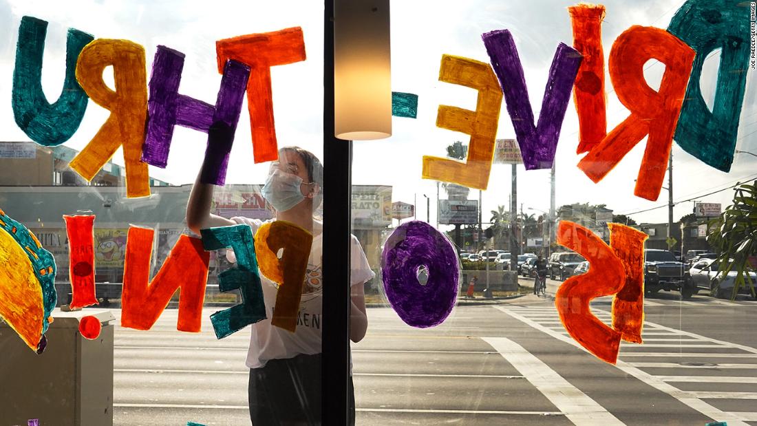 Amanda Gonzalez writes &quot;drive-thru is open!&quot; on the window of a Taco Bell restaurant in Miami on April 7.