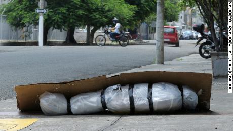 Un corp abandonat învelit în plastic și acoperit cu carton se sprijină pe un trotuar din Guayaquil, Ecuador, pe 6 aprilie.