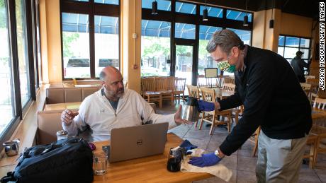 Manager cleans up a customer&#39;s table in the dining room of a restaurant that now offers dine-in service in Georgia. 