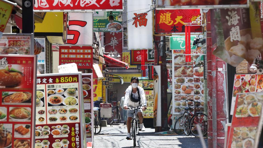 A man wearing a face mask cycles through Chinatown in Yokohama, Japan, on May 8, 2020. Prime Minister Shinzo Abe announced that Japan would extend its state of emergency until the end of May.