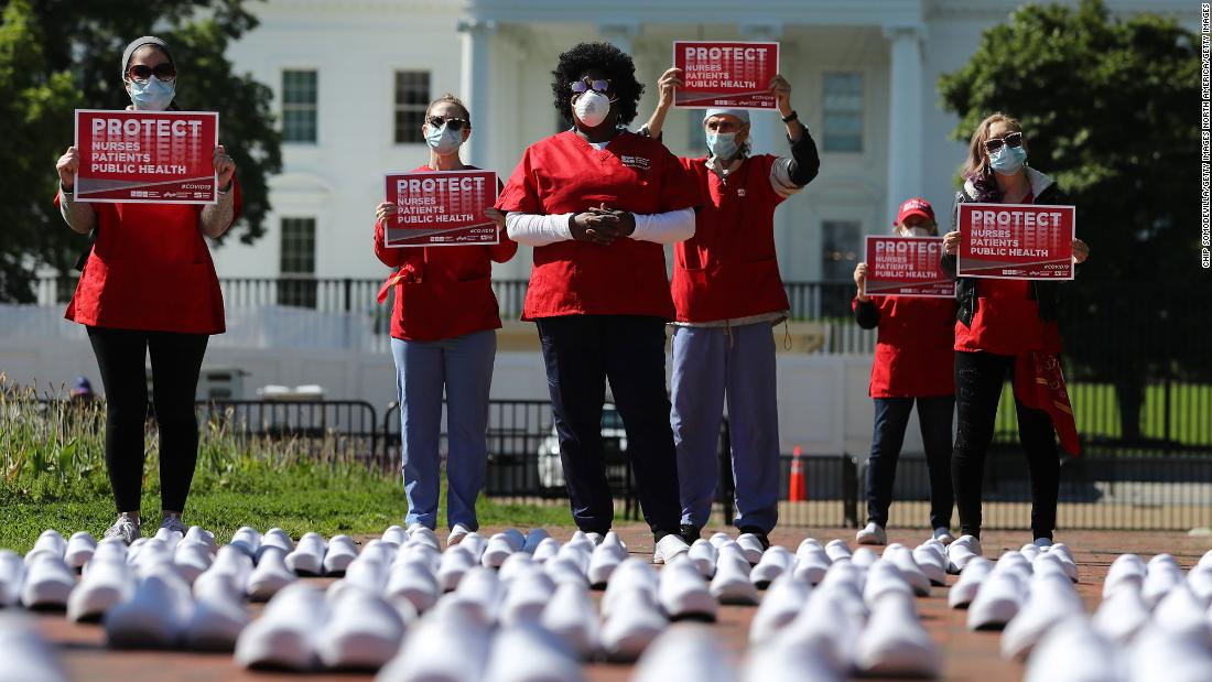 During a protest in Washington on Thursday, May 7, members of National Nurses United stand among empty shoes that they say represent nurses who have died from Covid-19.