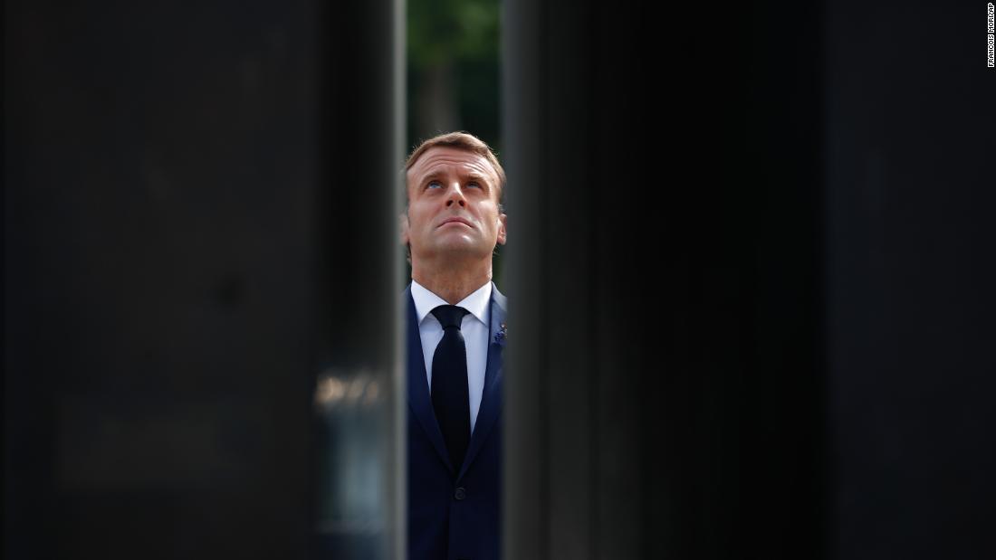 French President Emmanuel Macron looks up at the statue of Charles de Gaulle during VE Day ceremonies in Paris.