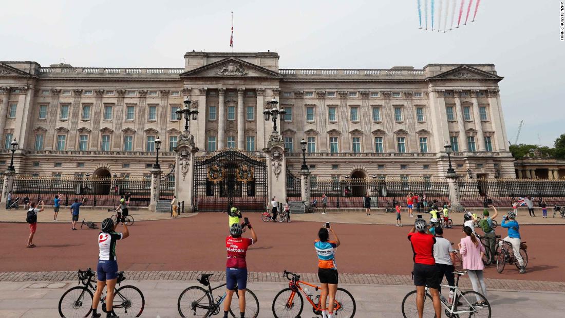 Cyclists watch as the Red Arrows fly over Buckingham Palace in London.