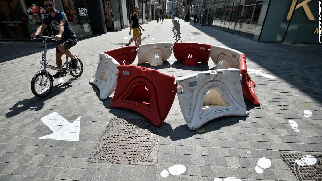 A man rides past social-distancing markers in front of a shop in Brussels, Belgium.