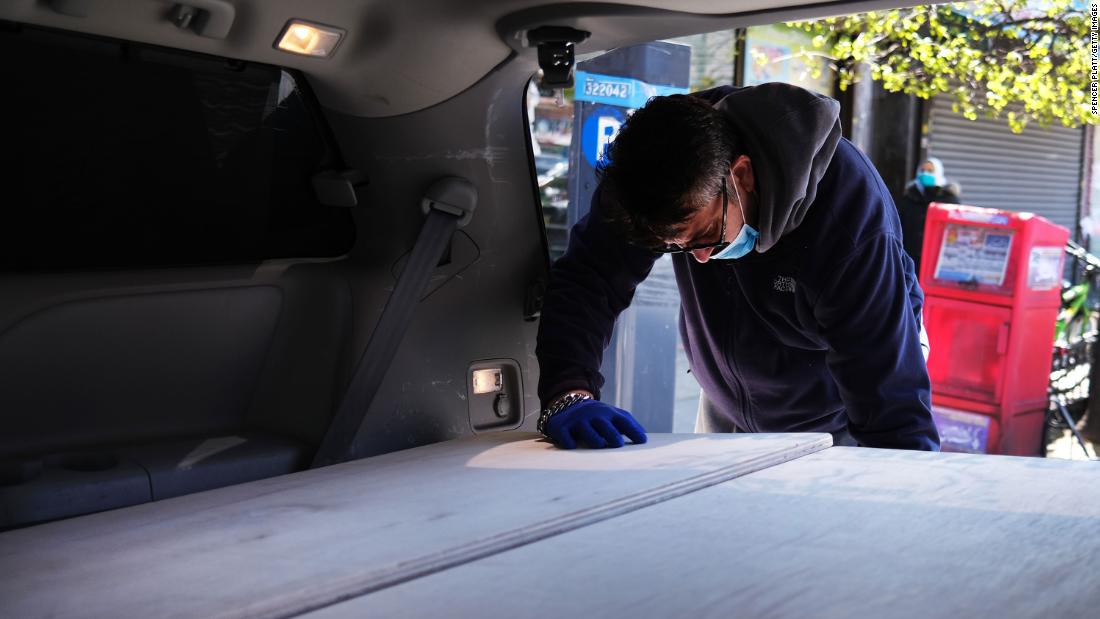 A man pauses as he places the casket of a relative into a van at a busy New York funeral home.