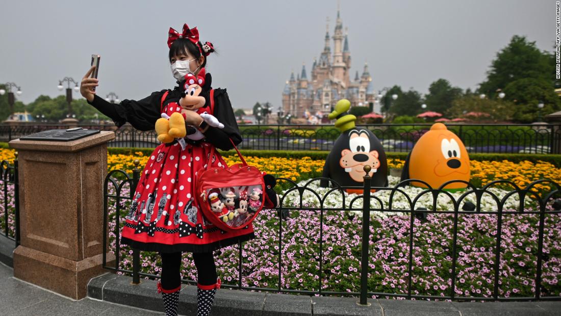 A woman takes a photo at Disneyland Shanghai after the amusement park reopened in China on May 11. The park had been closed for three and a half months. Visitors are now required to wear masks, have their temperatures taken and practice social distancing.