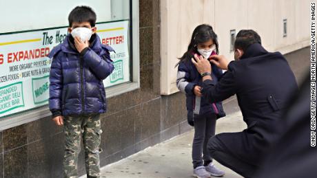 A man adjusts a child&#39;s protective mask amid the coronavirus pandemic.
