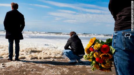 Relatives, friends and the surf community gather on The Hague Beach to mourn the loss of five surfers.
