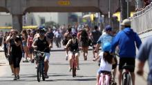 People ride and walk on a path along beach amid the coronavirus pandemic on May 15, 2020 in Huntington Beach, California.  Beaches across the state have started to reopen with rules in place such as maintaining social distancing and restrictions against lying or sitting down on the beach in order to slow the spread of COVID-19. 