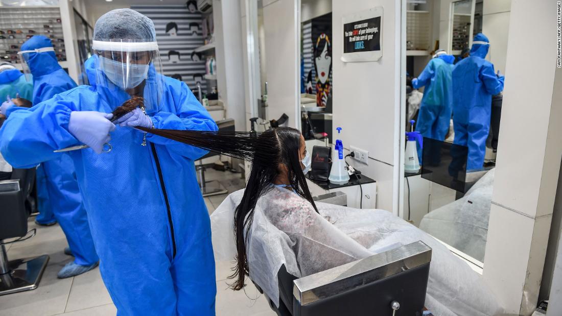 A worker wears protective gear while cutting a customer&#39;s hair at a salon in Nadiad, India, on May 17. India&#39;s lockdown was set to remain in place until May 31, but many salons and shops were able to reopen.