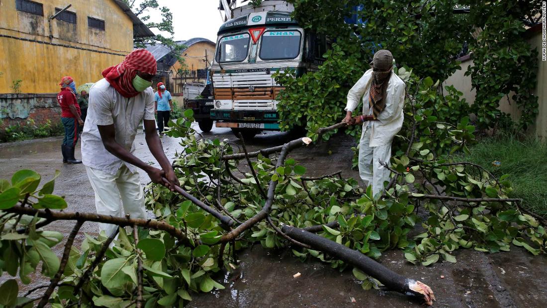 Rescue workers in Kolkata cut tree branches that fell on a truck due to heavy winds.