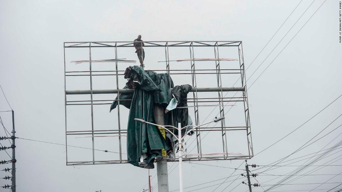 A worker removes a tarp from an advertising structure in Khulna, Bangladesh.