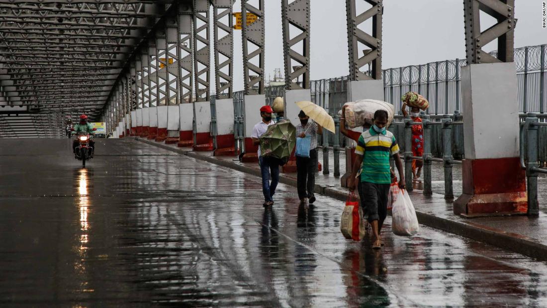 Commuters make their way along the Howrah Bridge in Kolkata as it rains on May 20.