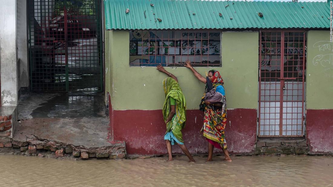 Residents walk along a house on a flooded street in Dacope.